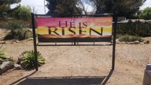 A sign that says he is risen on it.